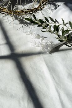 crown of thorns reminds the passion of the christ. resting on a white linen cloth with an olive branch
