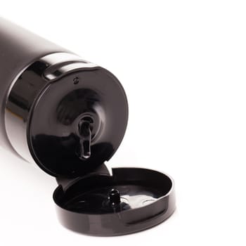 Opened lotion tube with black cap on a white table