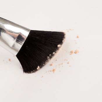 Makeup natural brush with beige powder on a white background