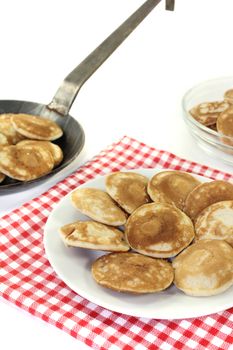 Dutch Poffertjes on a plate with pan before light background