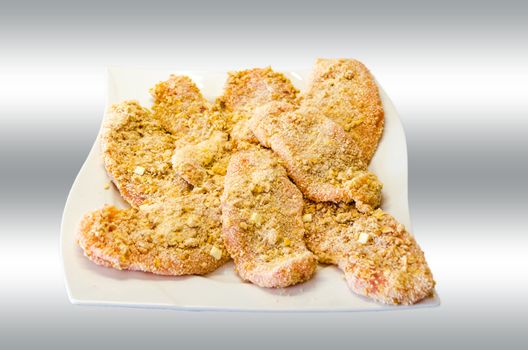 Breaded cutlet on a white plate with gray-white background.