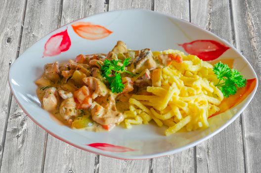 Zurich veal, Sliced ​​noodles with mushrooms and onions in cream on a red white plate