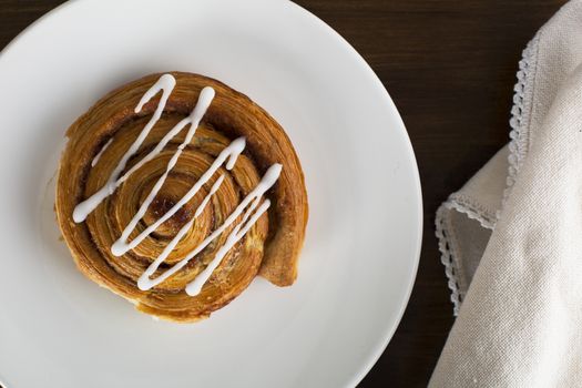 Cinnamon roll on plate with napkin, from directly above.