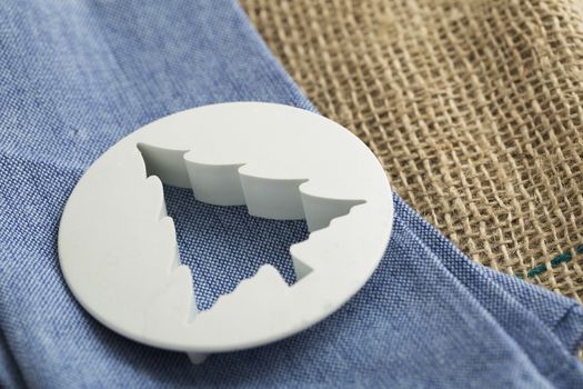 Plastic tree shaped biscuit cutter on blue napkin.