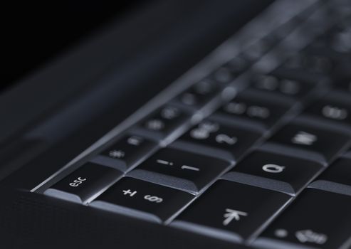 Closeup of backlit computer laptop keyboard selective focus on escape key ideal for technology night hacker standout
