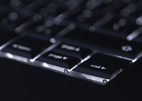 Closeup of backlit computer laptop keyboard selective focus on end key ideal for technology night hacker standout