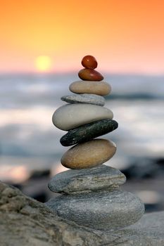 Pile of delicately balanced stones with the ocean and sunset in the background