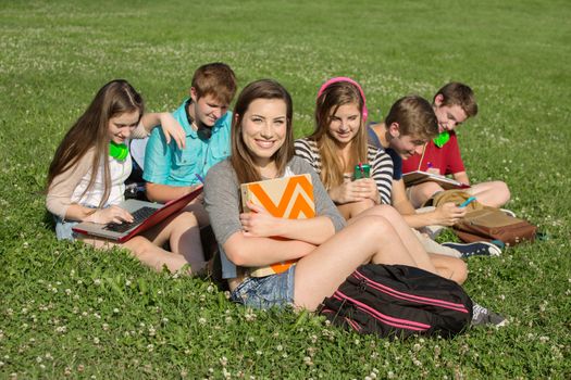 Cute teenagers sitting together studying outdoors