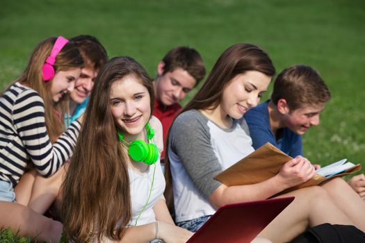 Happy teen girl with friends studying outdoors
