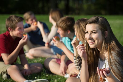 Cute female Caucasian teenager eating grapes with friends