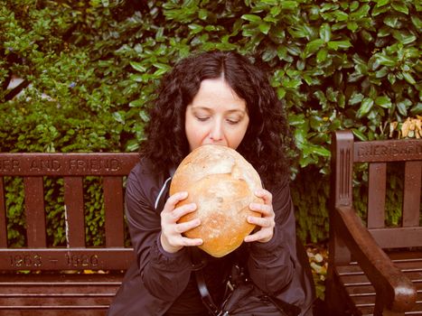 A portrait of hungry pretty young brunette eating huge bread