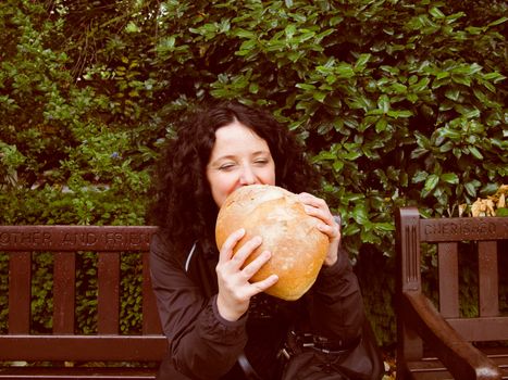A portrait of hungry pretty young brunette eating huge bread