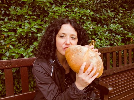 A portrait of hungry pretty young brunette eating huge bread