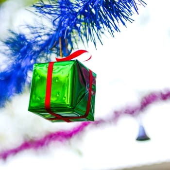Closeup green gift box, christmas ornament hanging on tree