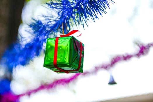 Closeup green gift box, christmas ornament hanging on tree