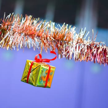 Closeup golden gift box, christmas ornament hanging on tree 