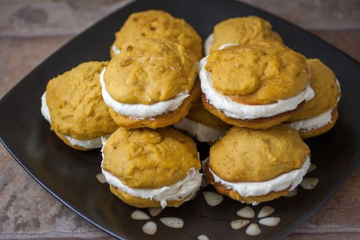 Pumpkin flavored whoopie pie cakes with whipped vanilla cream filling.