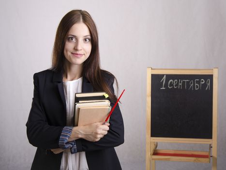 Portrait of the teacher. In the hands of the teacher's books and pointer. The teacher in the background stands the Board where it is written on September 1