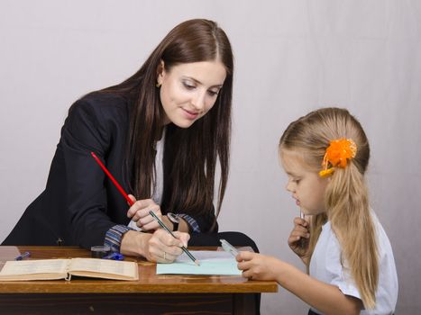 At the table sat a teacher and a student. Student teaches lessons, the teacher helps.