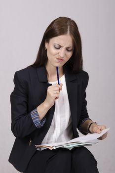 School teacher sits and checks notebook students. Teacher frowns reading what.