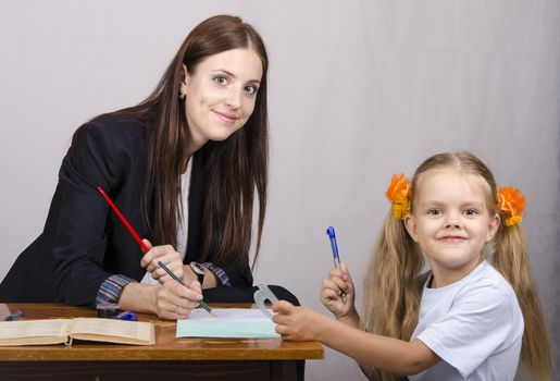 At the table sat a teacher and a student. Student teaches lessons, the teacher helps.