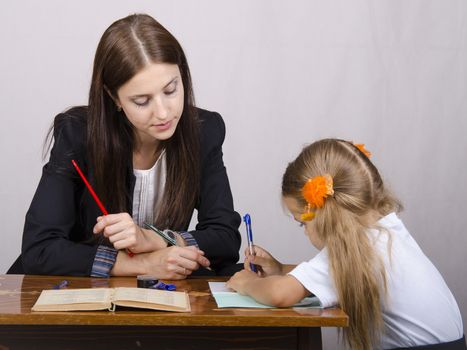 At the table sat a teacher and a student. Student teaches lessons, the teacher helps.