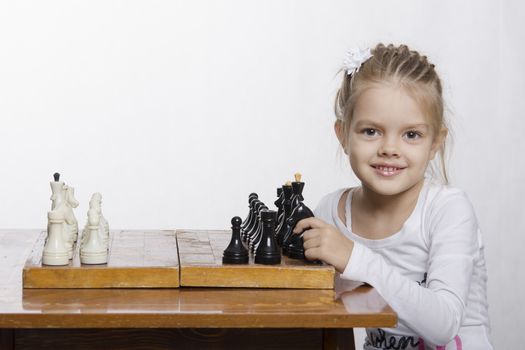 The girl sitting at the table, on which stands the chess Board. The girl is learning how to play chess