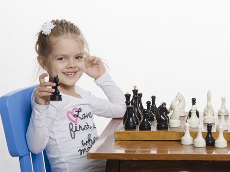 Four-year-old girl playing in chess. Girl fun looking at the Board,preparing to make the next move