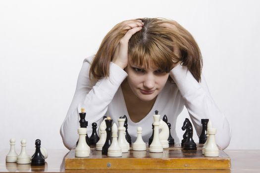  Young girl playing chess. Girl ponders the next move