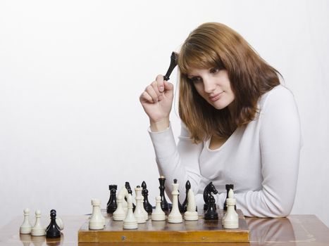 Young girl playing chess. A girl holds the shape of the Queen and thoughtfully, looking out the window