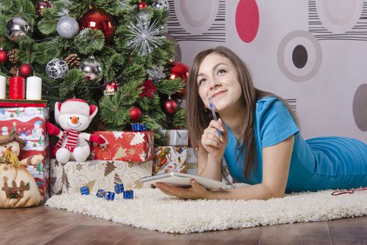 The girl lying on the carpet around the Christmas tree. She wrote a letter to Santa Claus