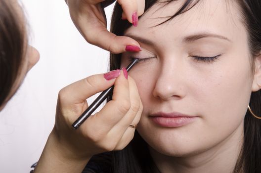 Makeup artist deals makeup on the model's face. She paints eyelashes model.