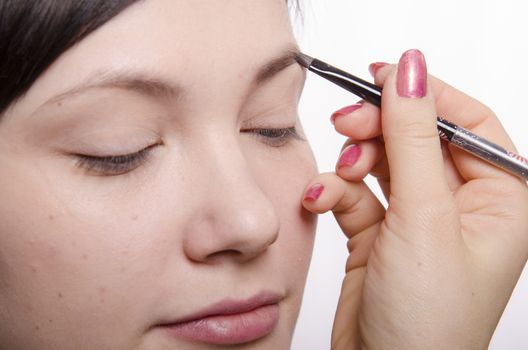 Makeup artist deals makeup on the model's face. She leads eyebrow pencil model.