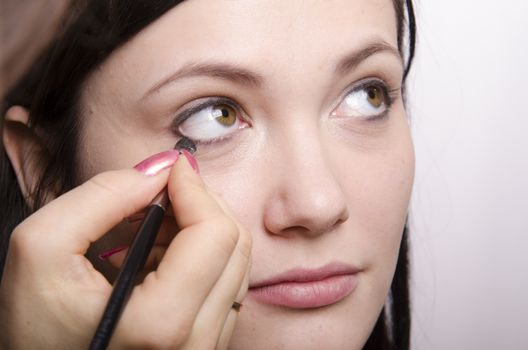 Makeup artist deals makeup on the model's face. She paints eyelashes model.