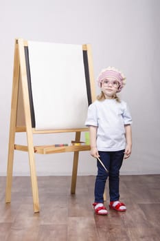 Three-year-old girl playing in the artist. Girl draws on the easel paints