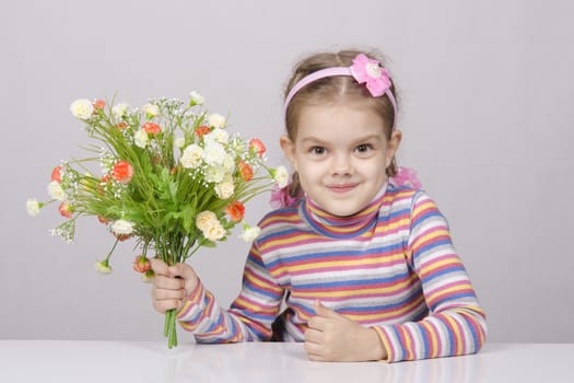 Girl with a bouquet of artificial flowers sitting at the table