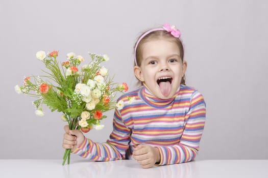 Girl with a bouquet of artificial flowers sitting at the table