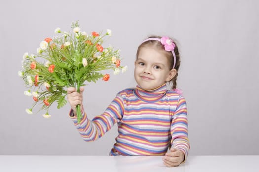 Girl with a bouquet of artificial flowers sitting at the table