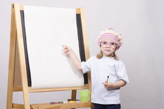 Three-year-old girl playing in the artist. Girl draws on the easel paints