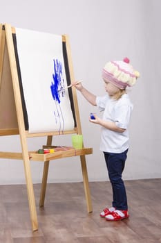 Three-year-old girl playing in the artist. Girl draws on the easel paints