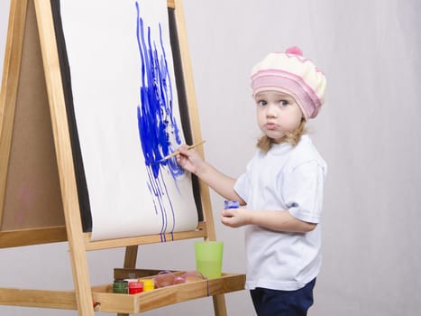 Three-year-old girl playing in the artist. Girl draws on the easel paints