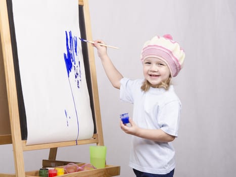 Three-year-old girl playing in the artist. Girl draws on the easel paints