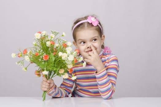 Girl with a bouquet of artificial flowers sitting at the table