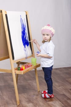 Three-year-old girl playing in the artist. Girl draws on the easel paints