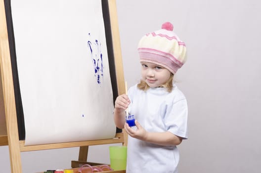 Three-year-old girl playing in the artist. Girl draws on the easel paints