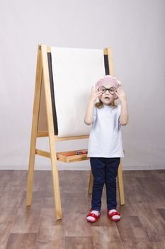 Three-year-old girl playing in the artist. Girl draws on the easel paints