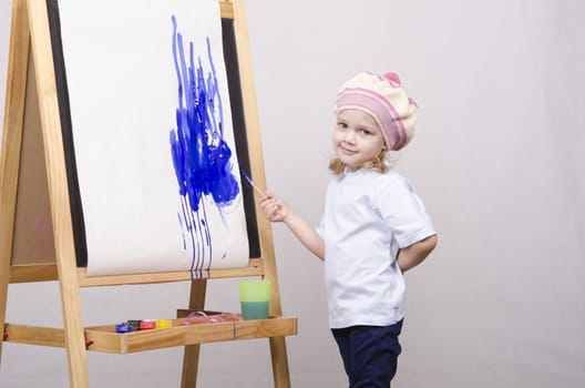 Three-year-old girl playing in the artist. Girl draws on the easel paints