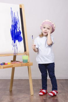 Three-year-old girl playing in the artist. Girl draws on the easel paints