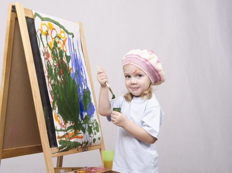 Three-year-old girl playing in the artist. Girl draws on the easel paints