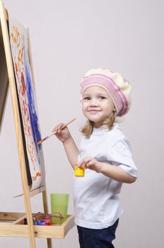 Three-year-old girl playing in the artist. Girl draws on the easel paints